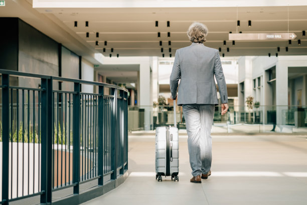 成熟的商人在机场带着行李走路的后视镜图片下载