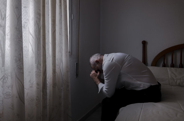 一个穿白衬衫的成年人坐在房间的床上图片下载