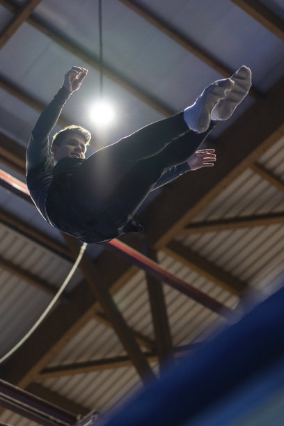 一个年轻人在运动中心的蹦床上跳。垂直和低角度视图图片下载