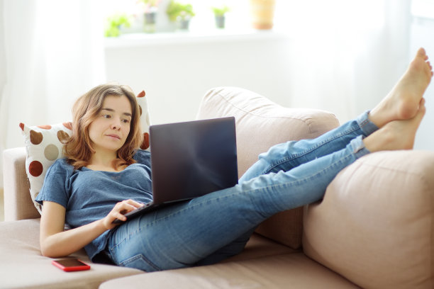 躺在沙发上用笔记本电脑工作的女人。自由职业者或博客。远程学习。额外的教育。再培训课程。网上业务。社交媒体上瘾图片下载