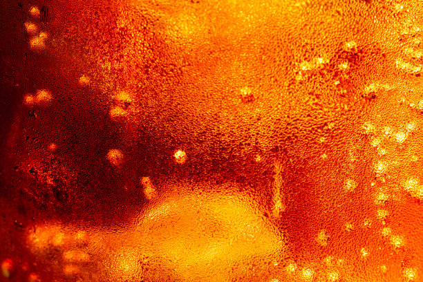 近距离观看在黑暗的可乐背景的冰块。清凉甜美的夏日饮品，泡沫和宏观气泡贴在玻璃墙上。发出嘶嘶声或浮到表面上。图片下载