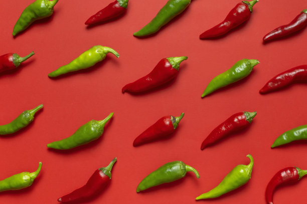 热的红色和绿色的新鲜辣椒在红色的背景平躺顶视图。菜肴调味料，烹饪用辛辣香料，辣椒，食物。创意布局，辣椒图案图片下载