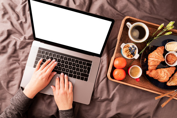 一个女人一边在笔记本电脑前工作，一边在漆黑的屏幕前吃欧式早餐图片下载