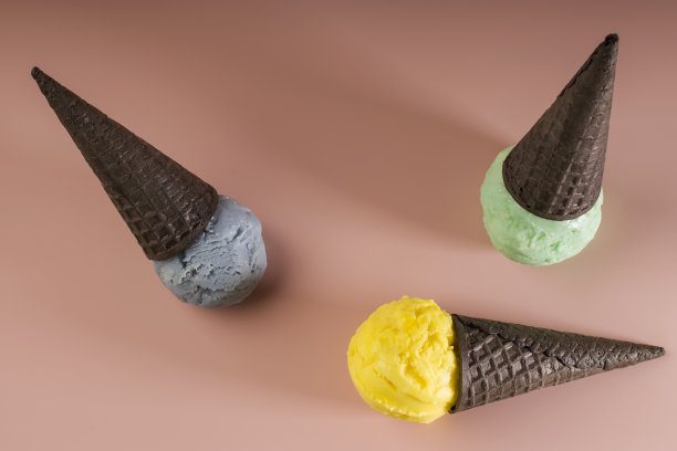 各种口味的冰淇淋倒华夫蛋筒在粉红色的粉彩背景上。夏季和甜点菜单的概念。图片下载