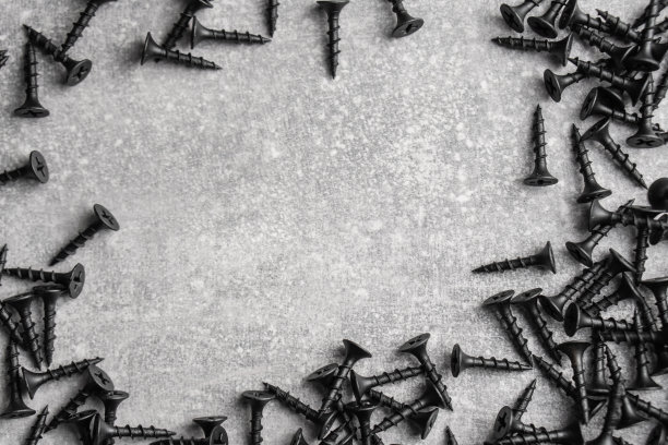 建筑五金。混凝土灰色背景上的自攻黑色螺钉。副本的空间。俯视图图片下载
