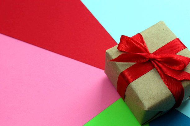 一个装着礼物的礼盒放在一张色彩鲜艳的彩色包装纸上。图片下载
