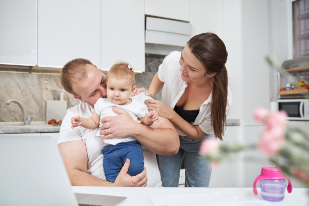 宝宝站在父亲的膝盖上，父母抱着它图片下载