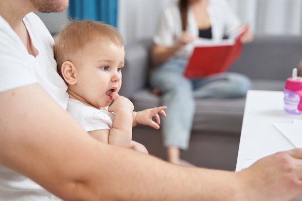 宝宝趴在爸爸的膝盖上，把手指放进嘴里图片下载