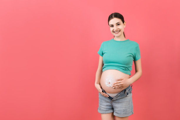 孕妇穿着没有拉链的牛仔裤，用保湿霜防止肚子上的妊娠纹。护肤概念图片下载