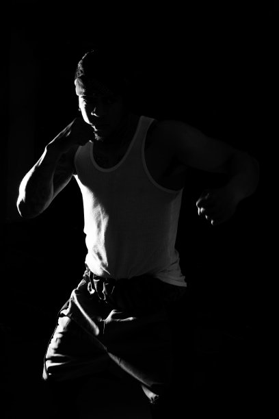 一个年轻人在黑色背景上练习太极拳。图片下载