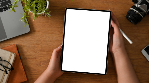 女摄影师或自由职业者手握写字板在木制的桌子上。图片下载
