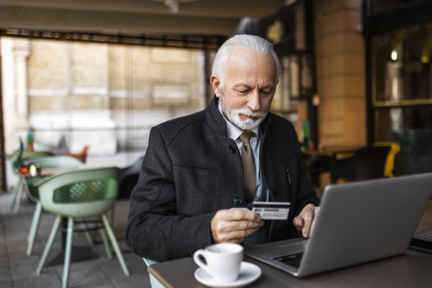 老人在咖啡厅用信用卡和笔记本电脑上网购物图片下载