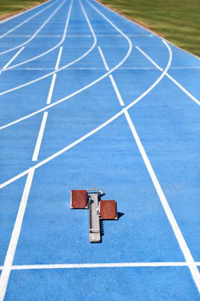 在跑道和田径场的蓝色跑道上起跑。运动配件。与复制空间背景的体育场地板的垂直作物。图片下载