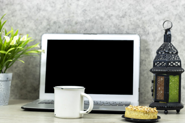 笔记本电脑与空屏幕为你的标志，或你的工作与百合花盆，咖啡和杏仁派在木桌上图片下载