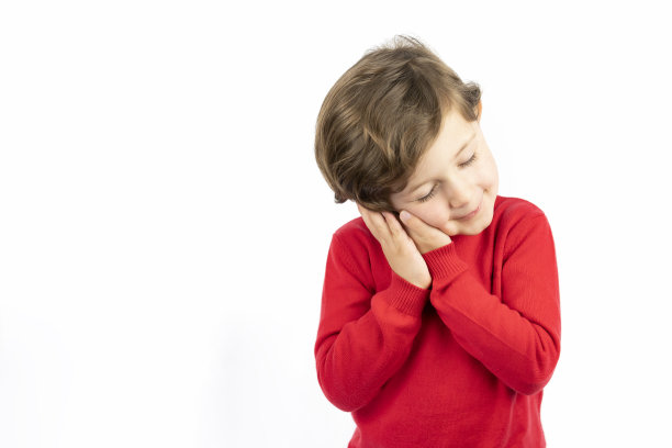 疲惫的孩子闭着眼睛，用手掌当枕头，假装睡着了，在白色的背景下看到了梦。图片下载