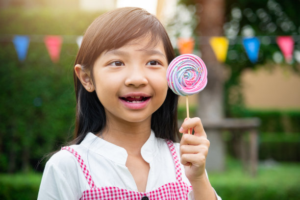 亚洲小女孩高兴地拿着彩虹蛋白糖在她的手中图片下载