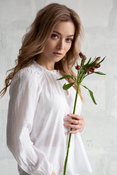 一幅性感迷人的女人的肖像，穿着白色的衬衫，手里拿着一朵花图片下载