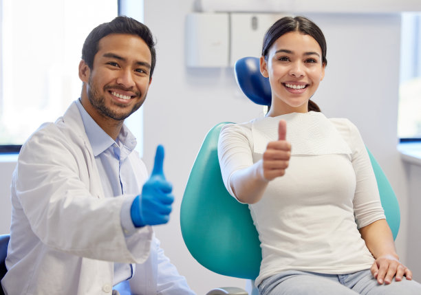 一名年轻女子在看牙医时竖起大拇指的肖像图片下载