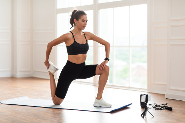 专注的女人用手机伸展腿部肌肉图片下载