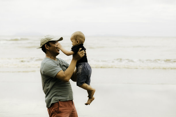 父亲在沙滩上抱着一个小男孩图片下载