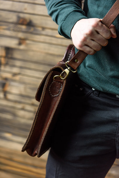 男子手中棕色皮包的特写照片图片下载