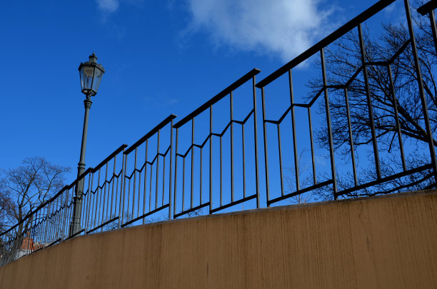 铺有天沟和装饰华丽的灰色金属栏杆的人行道。有玻璃灯罩和黑色灯柱的灯，在城市街道的旧煤气灯旁图片下载