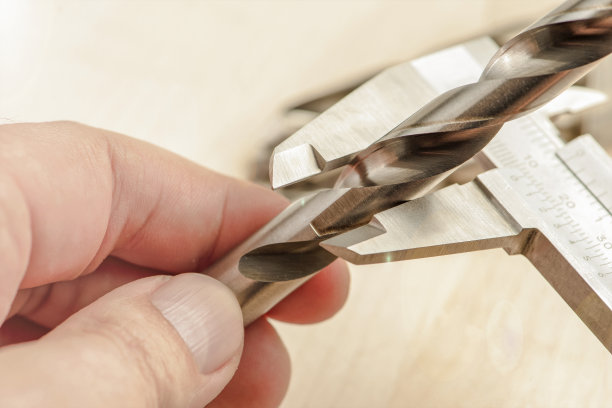 卡尺测量金属上的钻头，测量工业钻床上的钻具厚度。金属加工行业图片下载