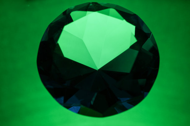 明亮的切割绿色钻石拍摄在工作室与彩色背景图片下载