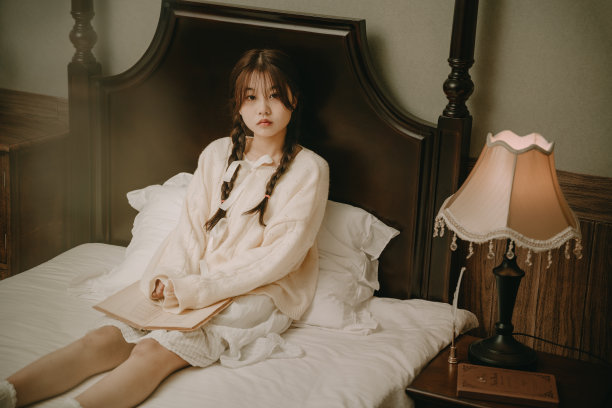 一个美丽的亚洲女孩在床上看书图片下载