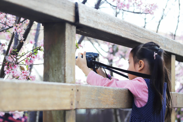一个亚洲女孩用数码相机拍照。图片下载