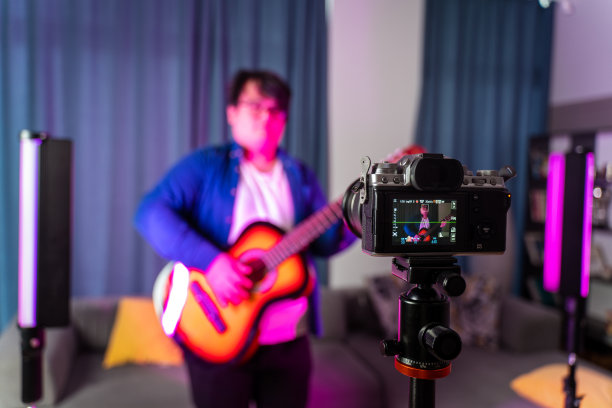 超重的男孩在家里拍视频，对着摄像机弹吉他图片下载