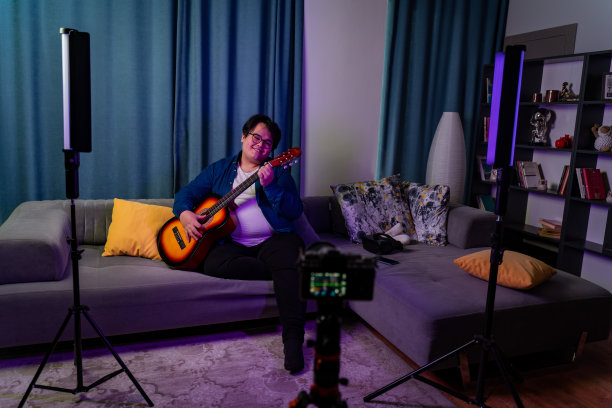 超重的男孩在家里拍视频，对着摄像机弹吉他图片下载