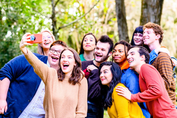 庞大的混合种族和性别的年轻朋友群体，z一代大学生，使用手机制作视频或自拍，以进行有趣的内容创作或社交媒体图片下载