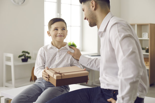 一个可爱的小男孩在父亲节给他的父亲一个礼物祝贺他的特写。图片下载