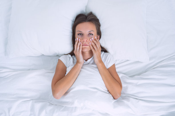 患有慢性疲劳或抑郁的疲惫困倦的妇女躺在床上。糟糕的早晨图片下载