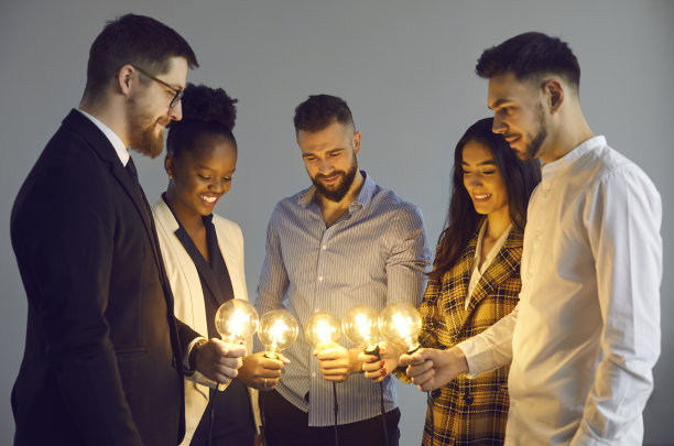商业团队拿着闪亮的灯泡，作为创意社区分享想法的象征图片下载