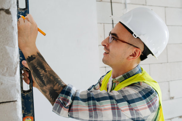 戴着白色头盔，一丝不苟的建筑工程师在墙上做记号图片下载