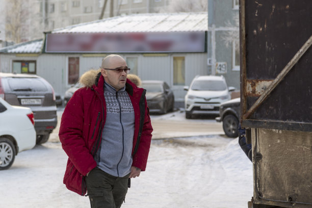 一个光头男人在工作场所穿着一件没扣的红色羽绒服图片下载