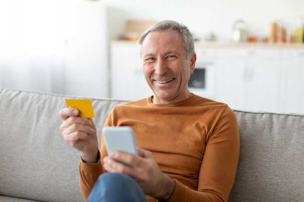 成熟的男人在家使用手机和信用卡图片下载