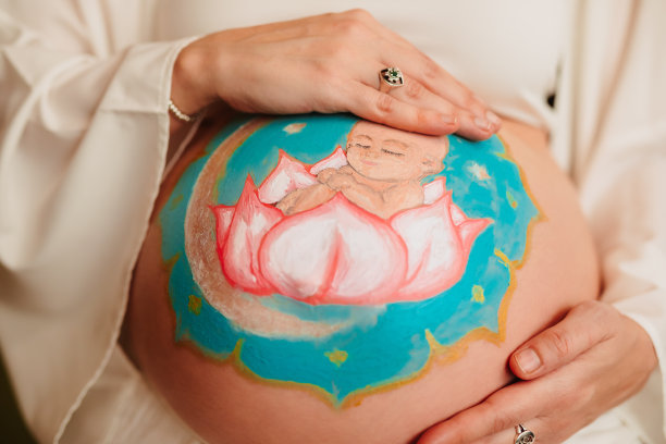 一个孕妇的艺术画的腹部与婴儿曼荼罗的腹部与她的手的特写。图片下载