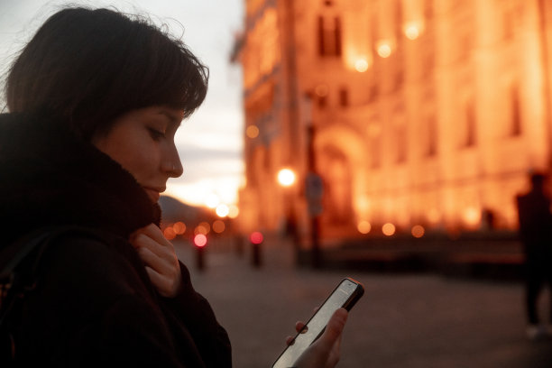 年轻女子在街上用智能手机图片下载
