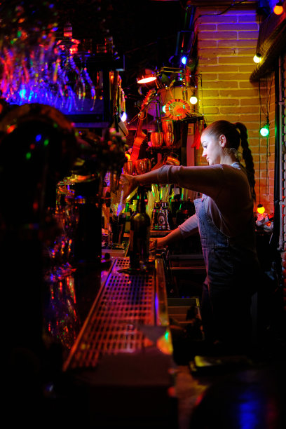 女酒保在酒吧工作时准备饮料。图片下载