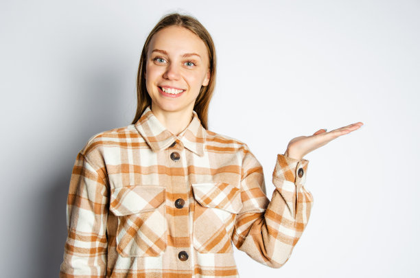 一个微笑的女孩把她的手掌放在一边，看着镜头。广告的概念图片下载