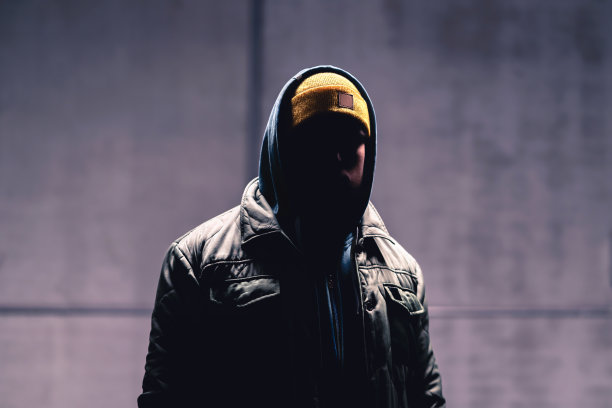 黑暗中的蒙面罪犯。戴兜帽的神秘男人。城市街道上的流氓。连帽衫的流氓。隐藏着脸的跟踪者。图片下载