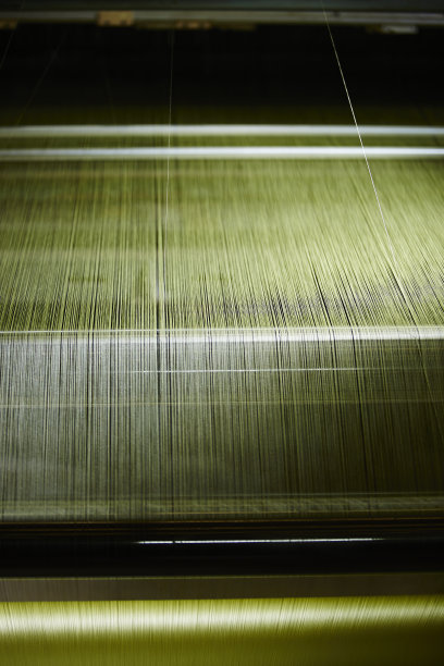 介绍了绿色丝线在织布机中的运行过程。在纺织厂生产。工业用织物生产线，传统工艺在织布机上图片下载