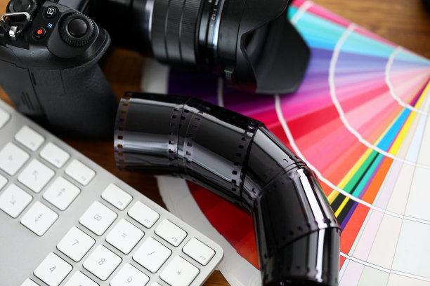 旧胶片胶带铺在彩色扇尾和银色键盘上图片下载