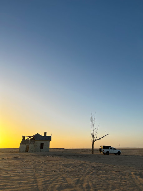 一辆越野车停在枯树和格鲁布火车站附近。Kolmanskop图片下载