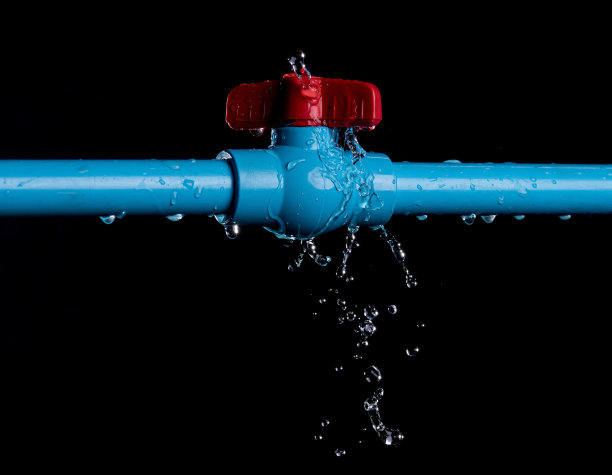 渗漏和飞溅的水从PVC塑料管上的黑色背景。图片下载