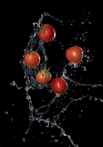 新鲜的红色番茄在溅水孤立在黑色背景上图片下载