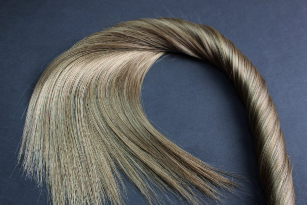 一缕棕色的头发躺在黑色的背景上图片下载